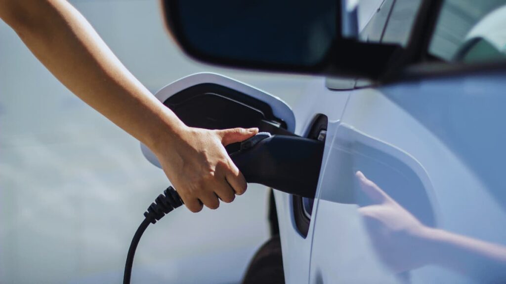 Close-up van een witte wagen die elektrisch wordt opgeladen.